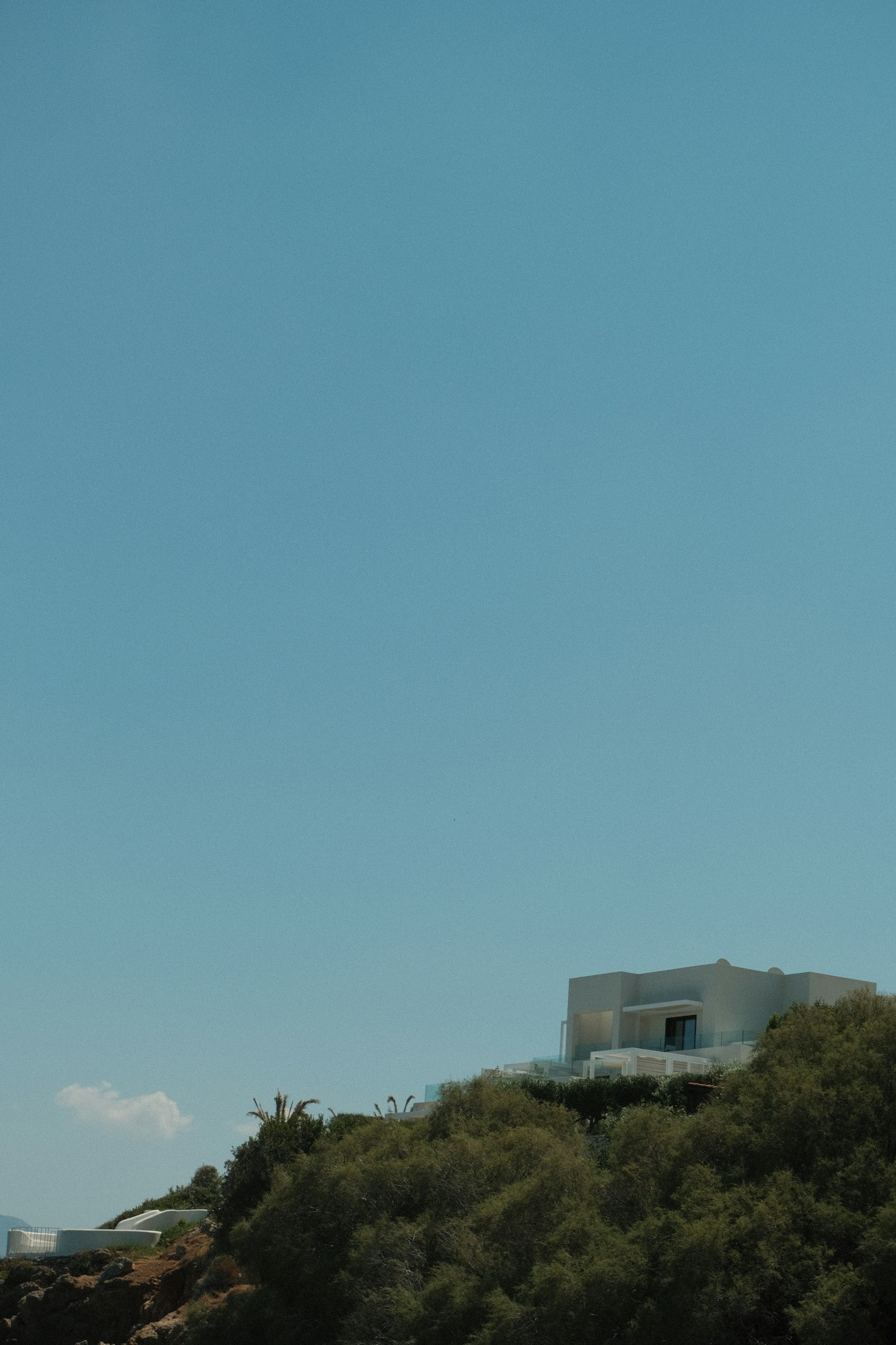 White modern villa on a green hillside beneath a clear blue sky