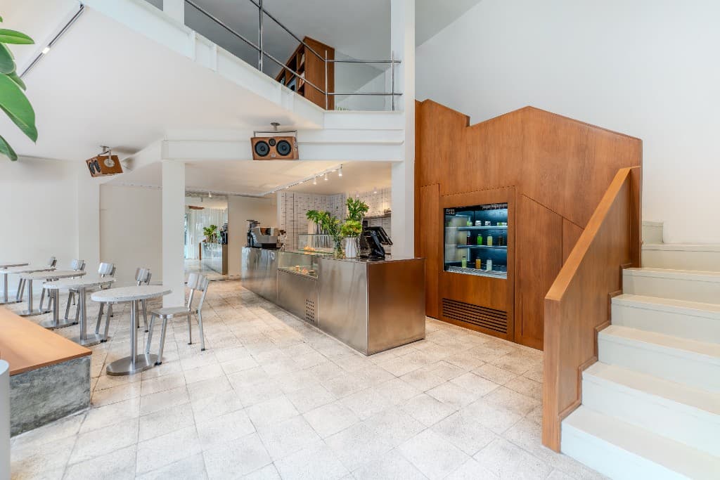 Bright modern cafe interior with service counter, seating, and wooden display wall